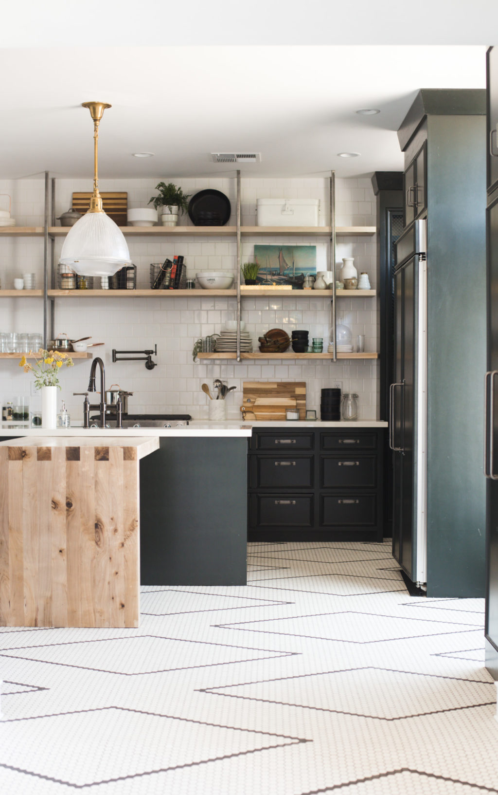 Dark green kitchen cabinets and hand laid black and white tile flooring (it's a DIY with a tutorial!!) are the star of this renovated kitchen. The bleached walnut island and open shelving fill the space with warmth. #kitchen #vintage #renovation #whitetile #openshelving 