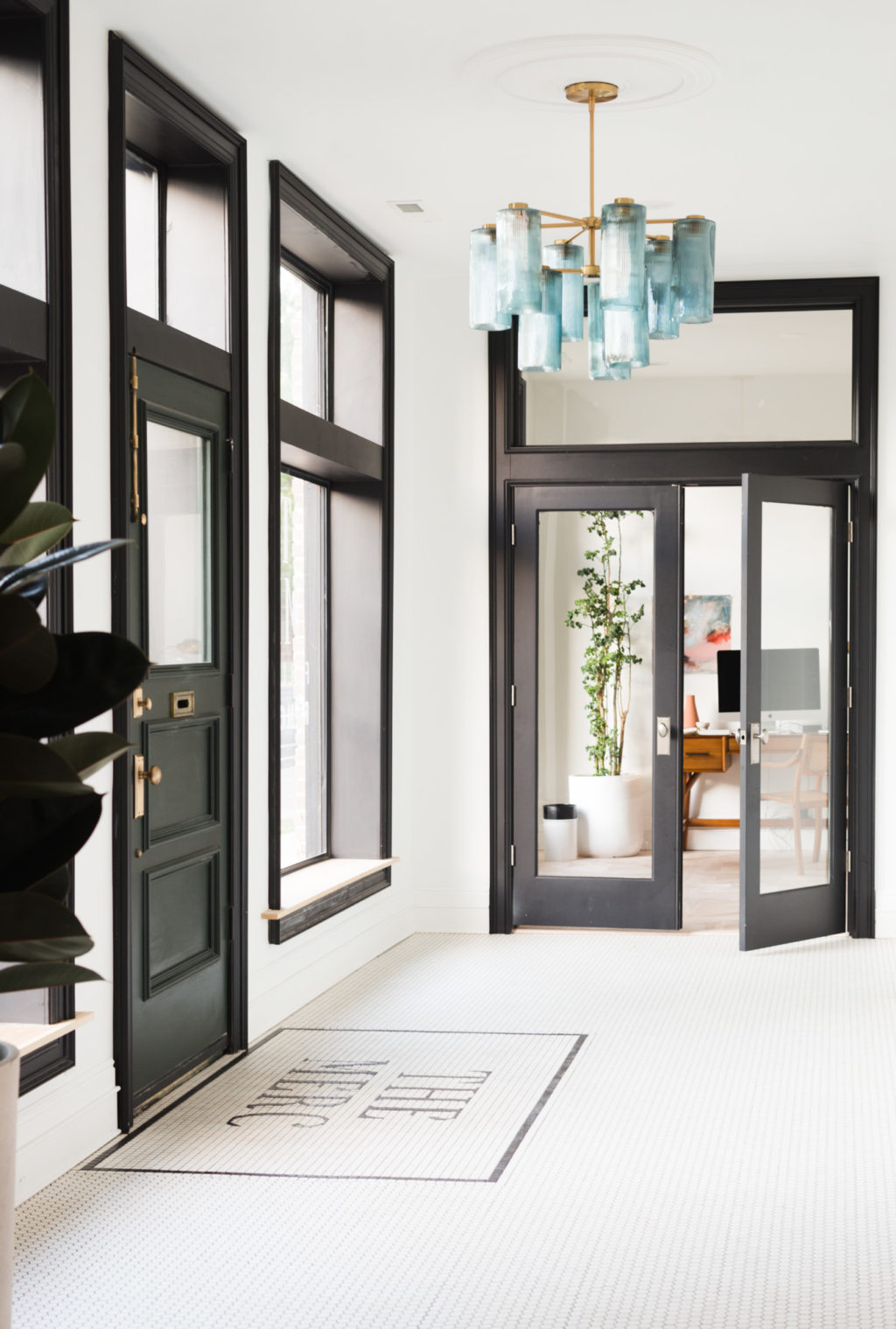 Black cased windows with window seat and dark green front door make this entryway pop. The custom lettered tile and blue glass chandelier add so much to this historic renovation! Get the full DIY details on Vintage Revivals!!s